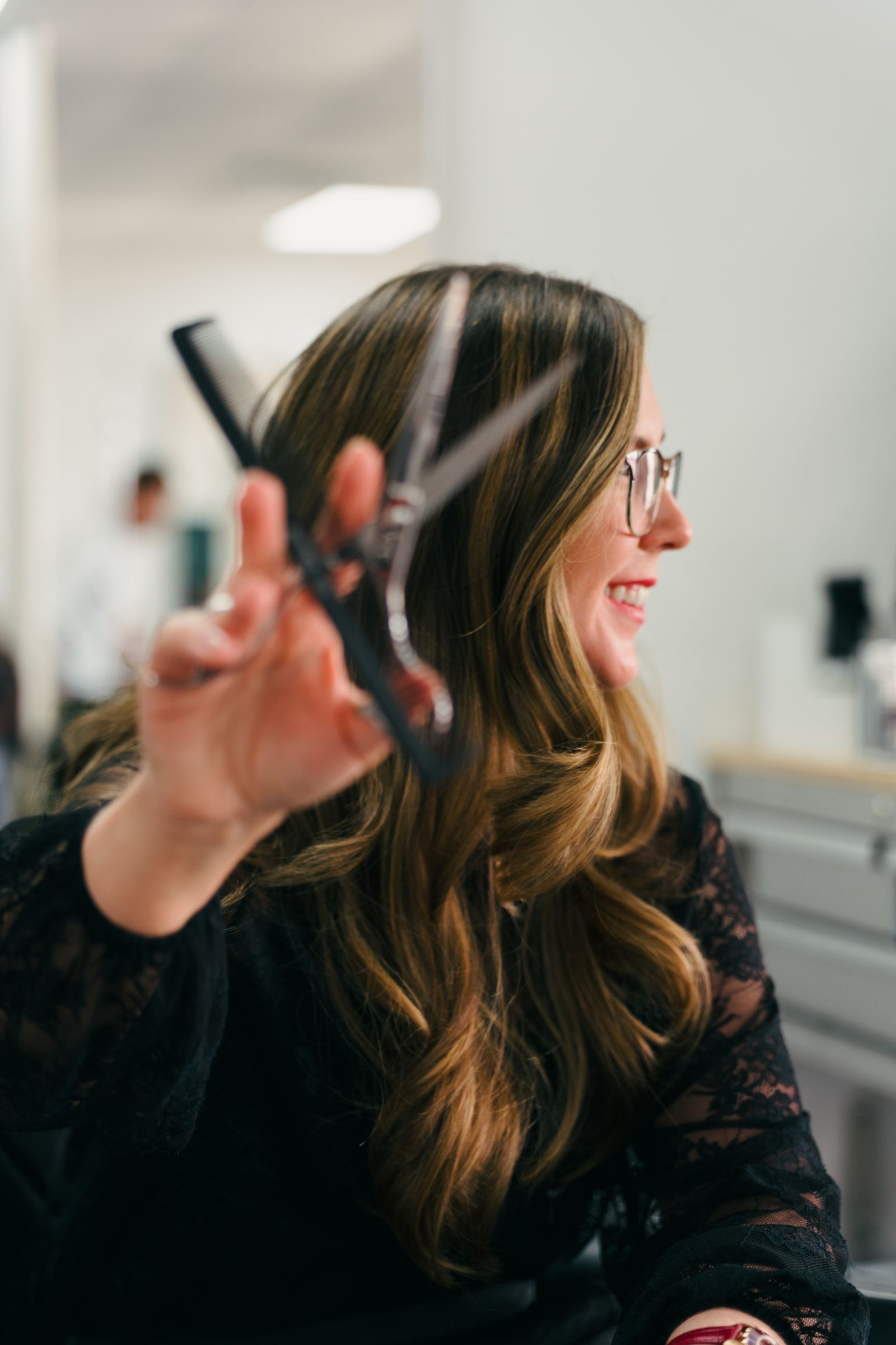 Danielle cutting hair with shears and a comb at Inspire Hair Studio
